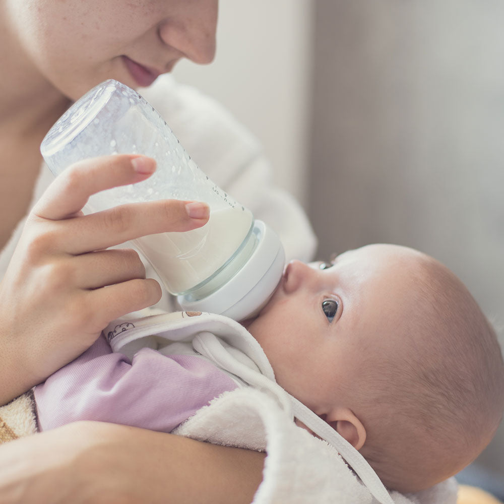 An infant being bottle-fed with Niuriss infant formula