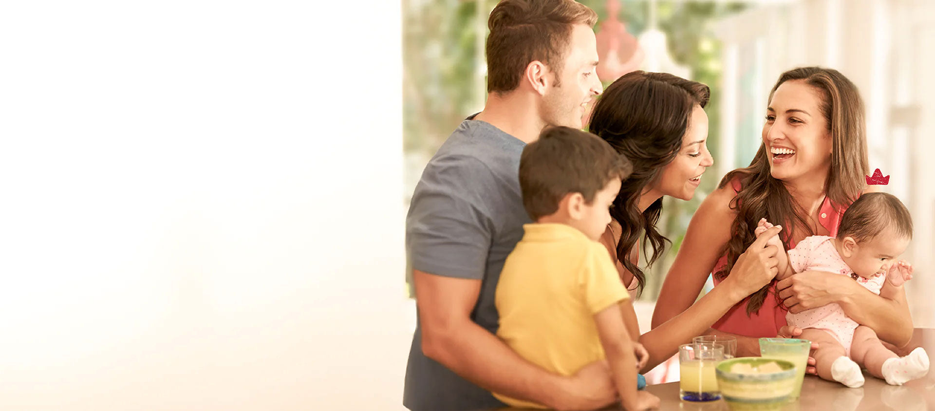 A group of parents and kids smile around a baby with a Niuriss crown, having joined the Nest to manage their formula budget.