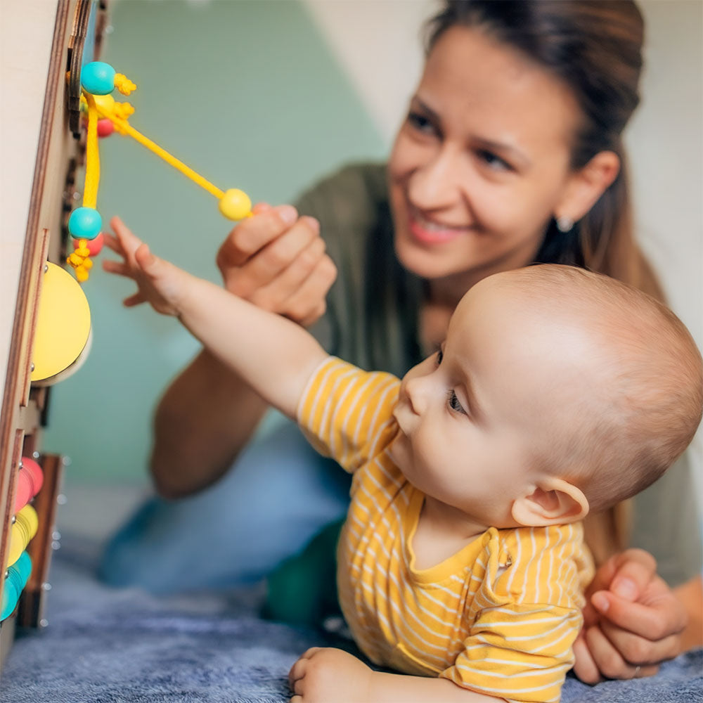 A baby is engaged playing a learning game, supported by impactful ingredients like GOS, DHA, ARA, nucleotides, and lutein.