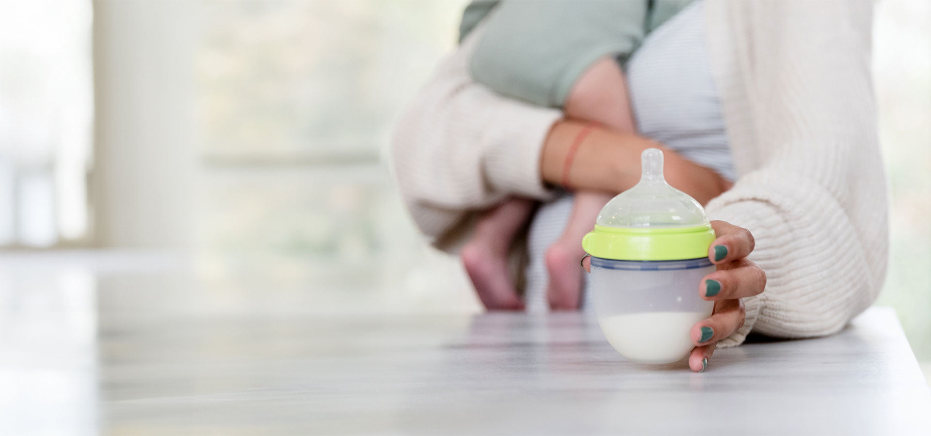 A mom reaching for a bottle of formula on the counter, confident having read our feeding guide.