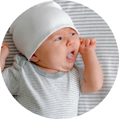 A baby yawns as they lie in their crib, his feeding needs taken care of.