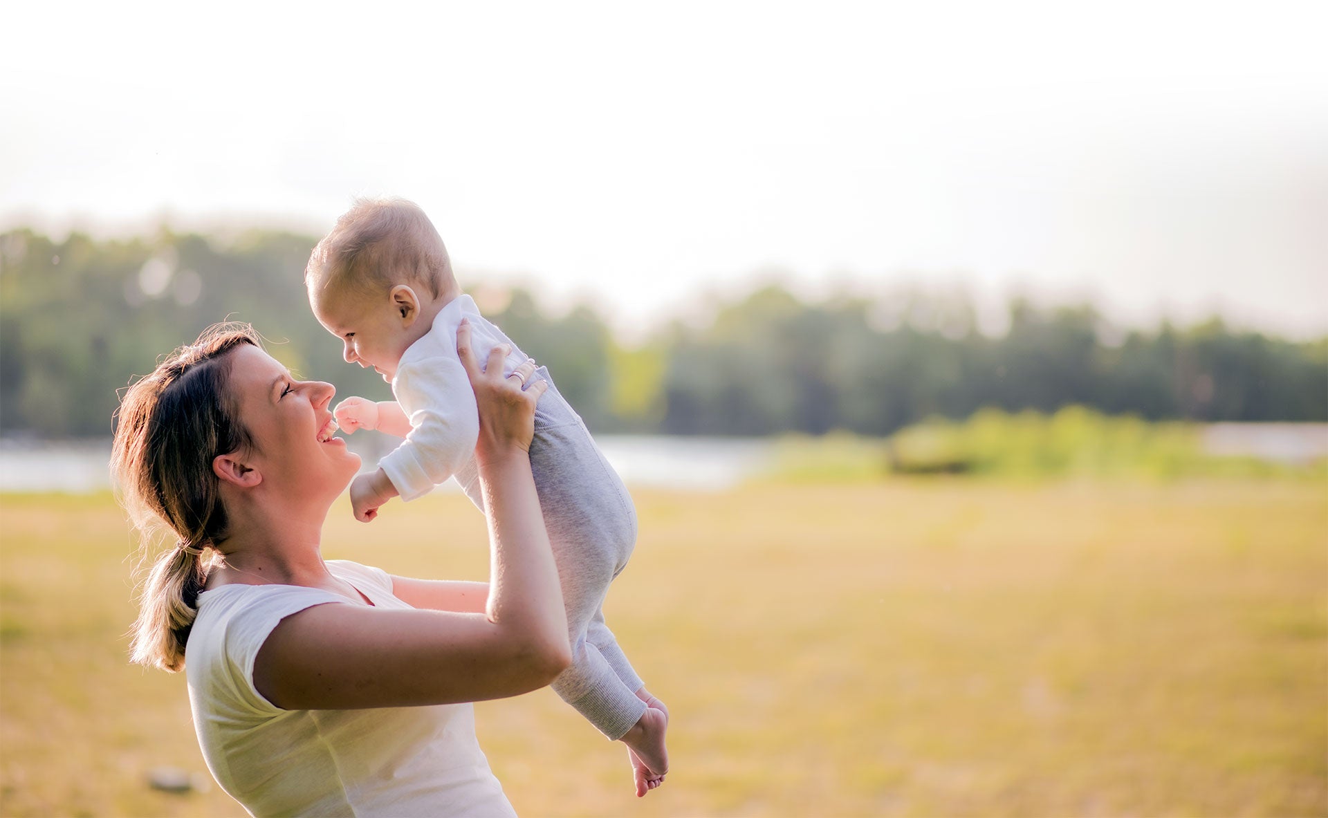 mom lifting her baby at the park on a sunny day