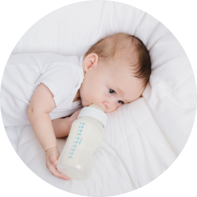 Baby comfortably laying down holding his milk bottle feeder 